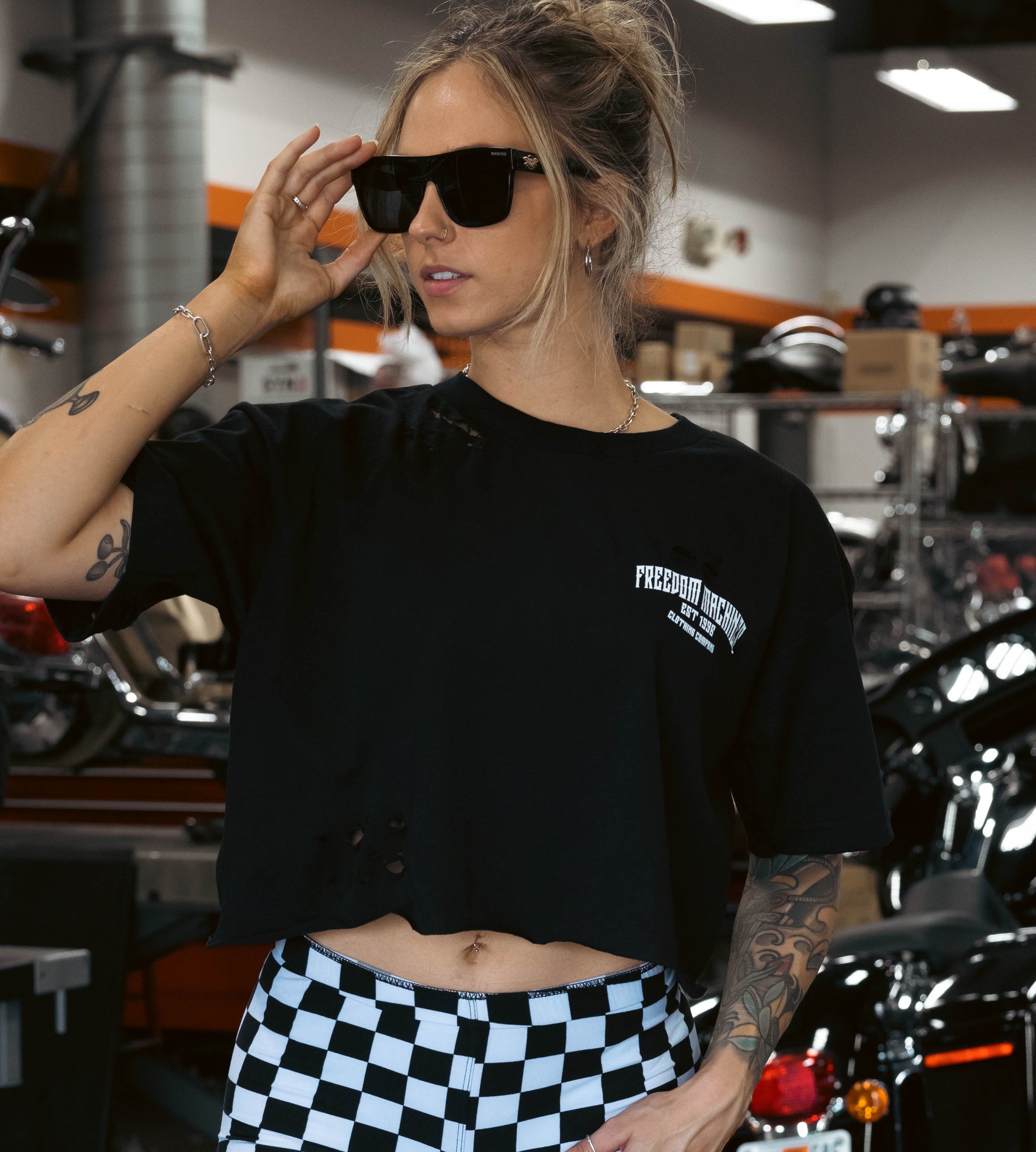Hand distressed black crop top for women. Picture is taken in a motorcycle garage. 